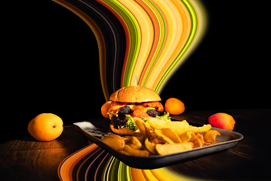 Burger mit Pommes auf einem Tablett, dahinter bunte Lichtspuren
