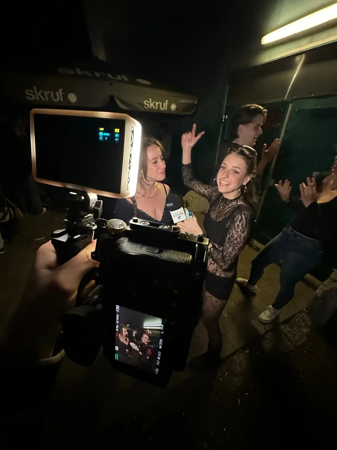 Kamera mit Monitor und Videolicht filmt feiernde Gäste in der Eventstage