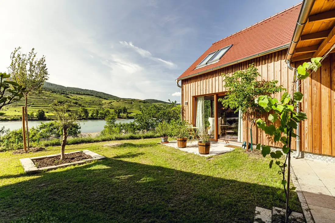 Holzhaus mit Garten, im Hintergrund die Donau und Weinterrassen