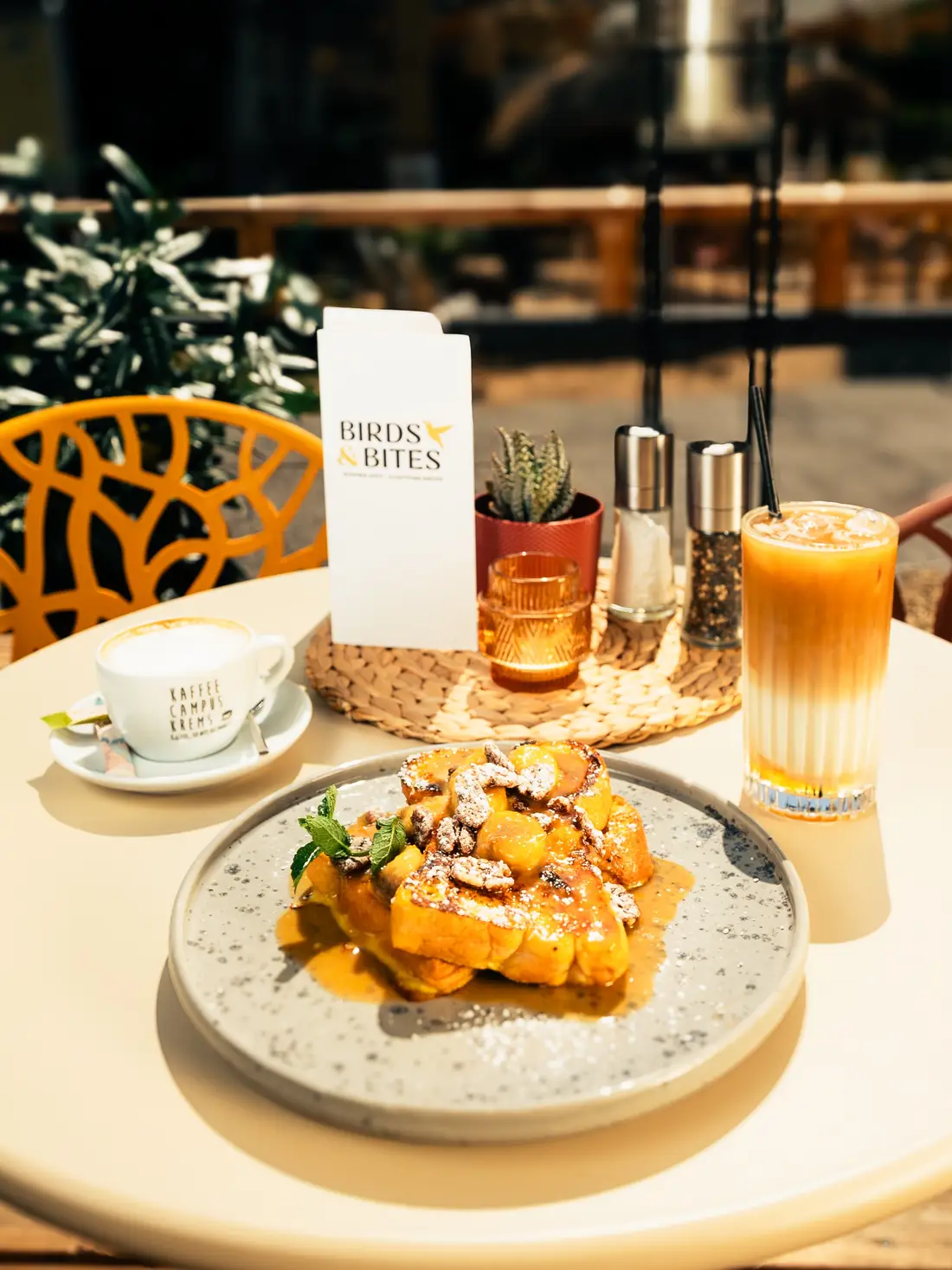 Outdoor breakfast table with French toast, coffee and a Birds & Bites menu
