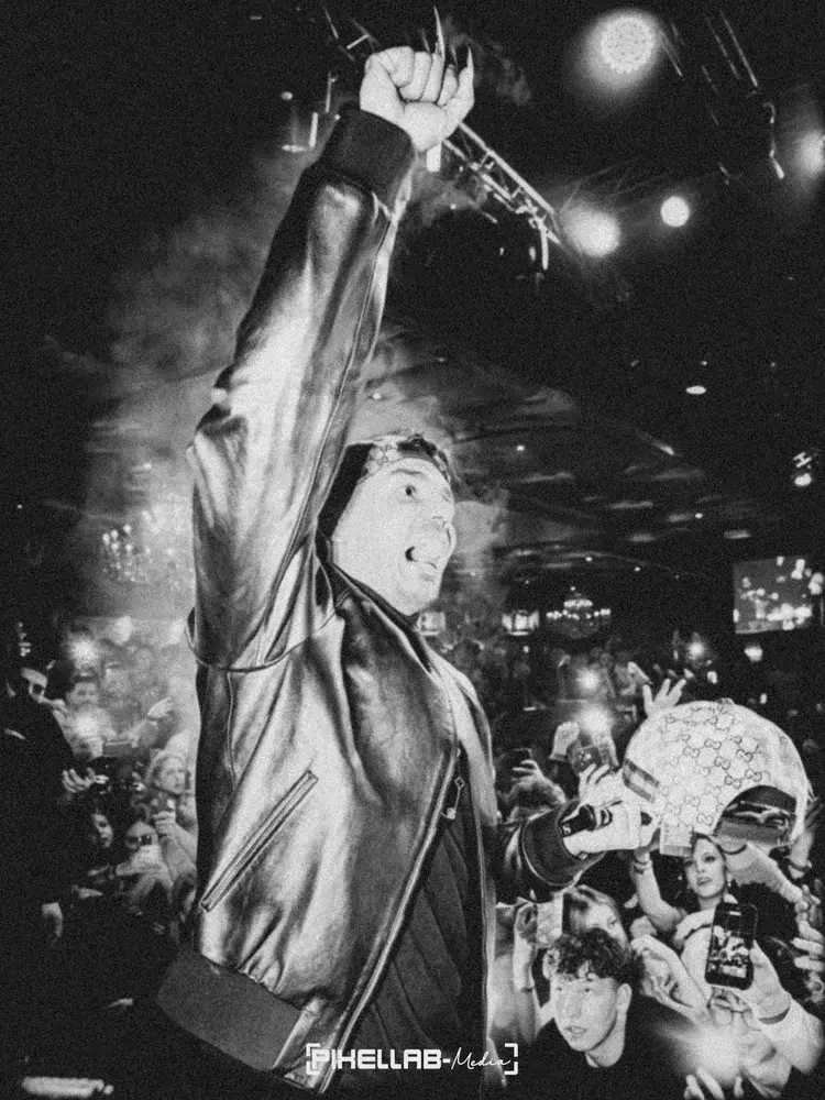 Rapper in Lederjacke reckt die Faust vor dem Publikum, Schwarz-Weiß-Foto