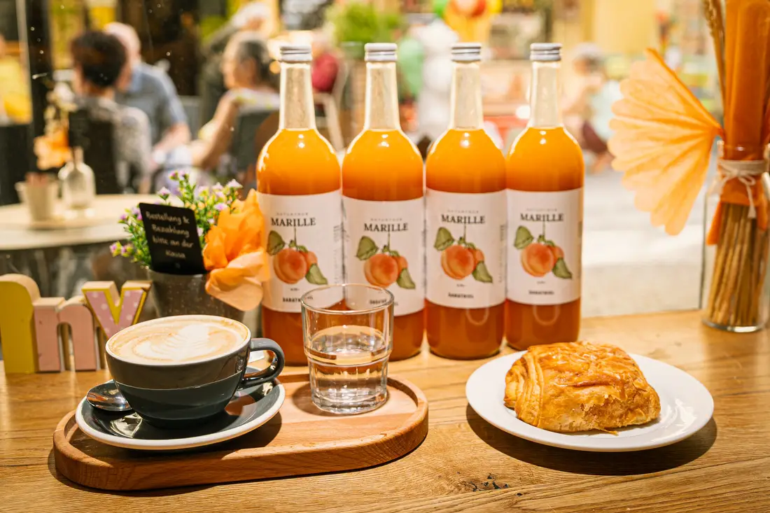 Bottles of apricot juice, coffee and pastries on a café table