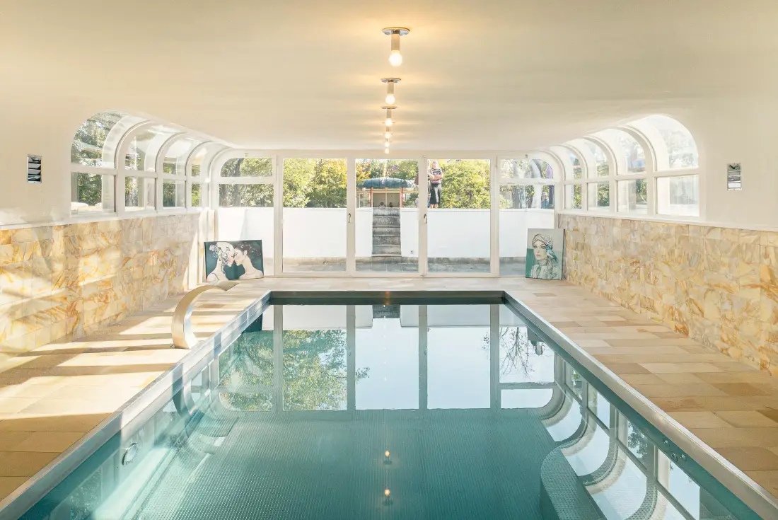 Hallenbad mit Rundbogenfenstern und Kunstwerken an den Wänden