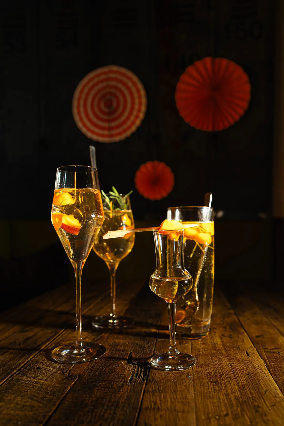Three spritz drinks in stemmed glasses against a dark background