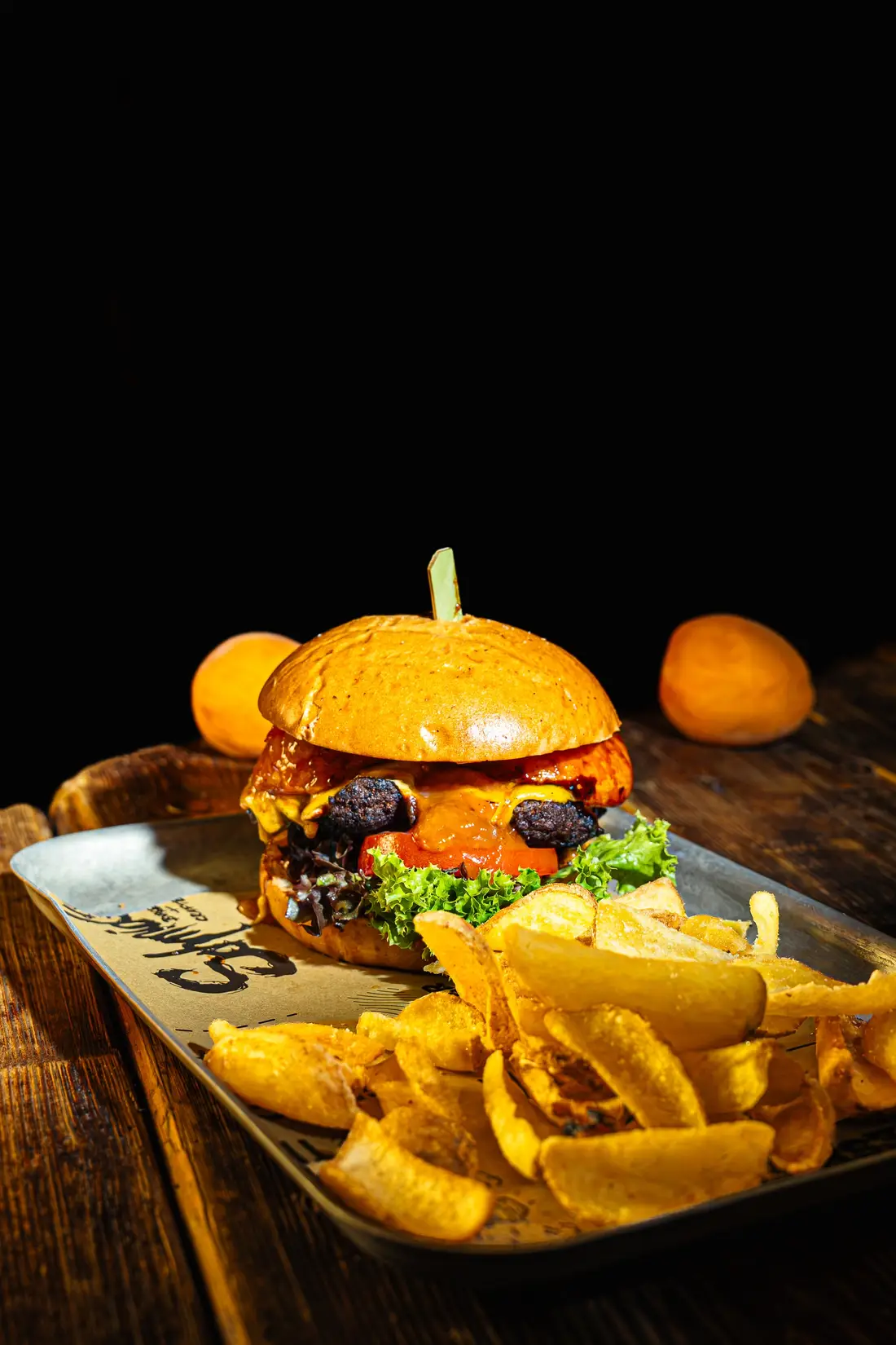 Burger with fries on a tray against a dark background