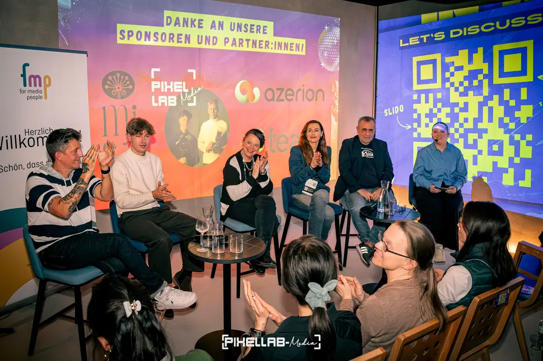 Panel discussion in front of an audience, sponsor logos on the screen behind, including Pixellab-Media