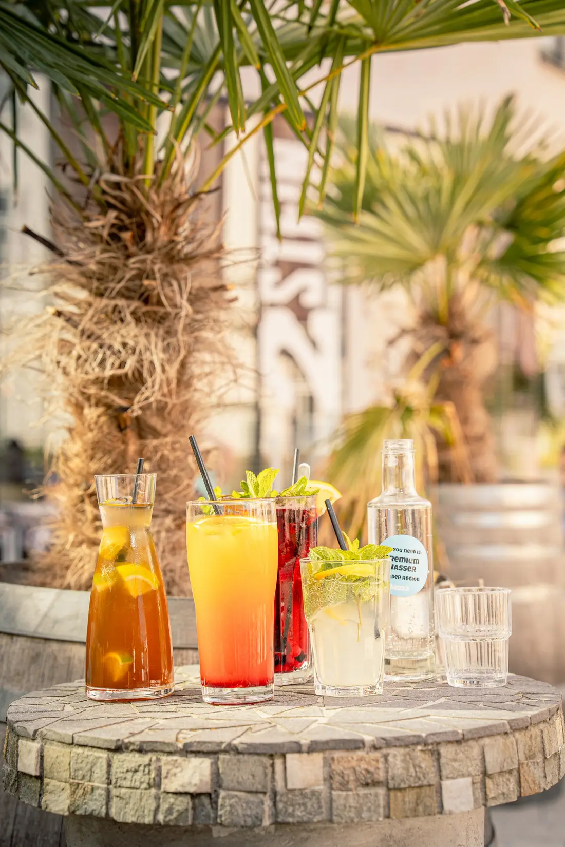 Colourful summer drinks on a stone table under palm trees
