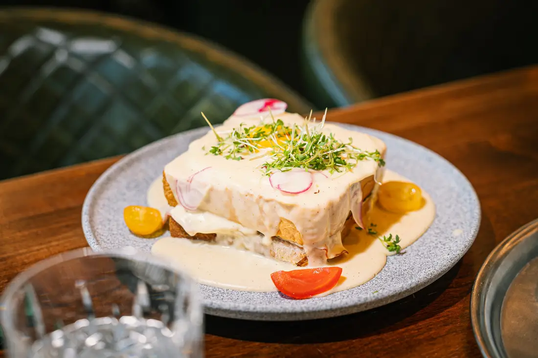 Toasted sandwich with light sauce, cress and radishes on a grey plate