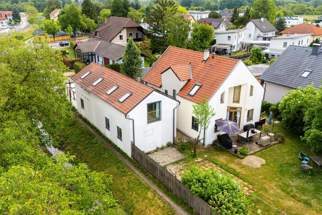 Luftaufnahme eines weißen Wohnhauses mit Nebengebäude und Garten in einer Siedlung