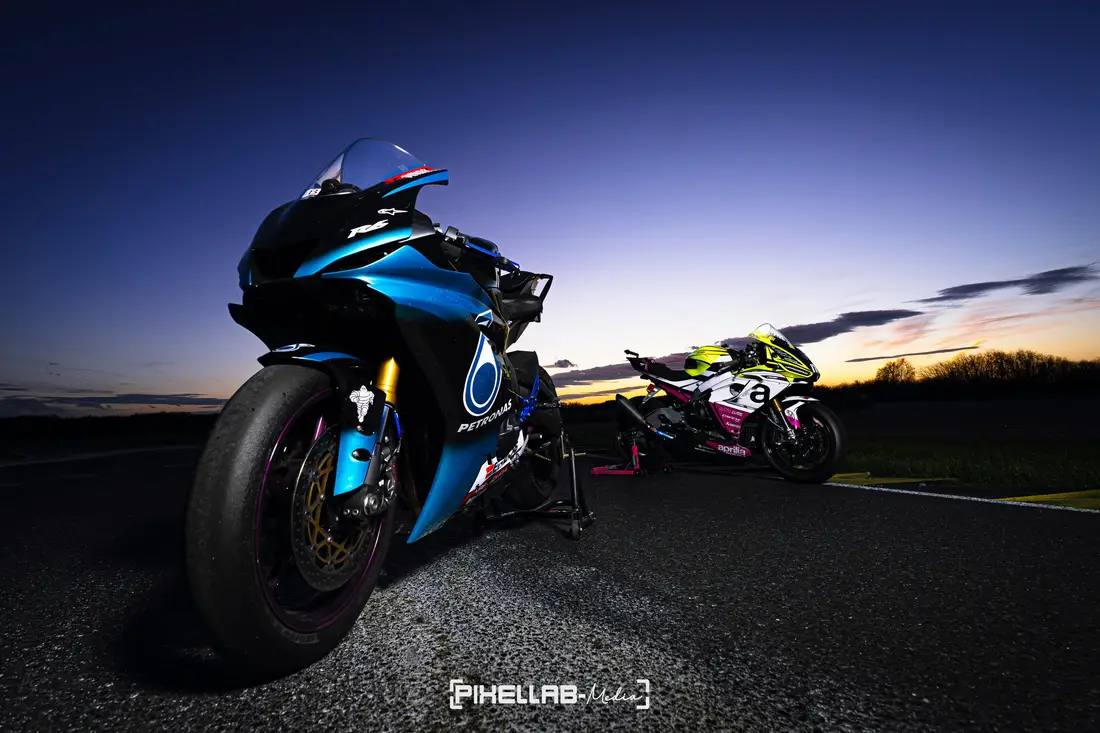 Blue racing motorbike from a low angle at dusk, a second motorbike behind