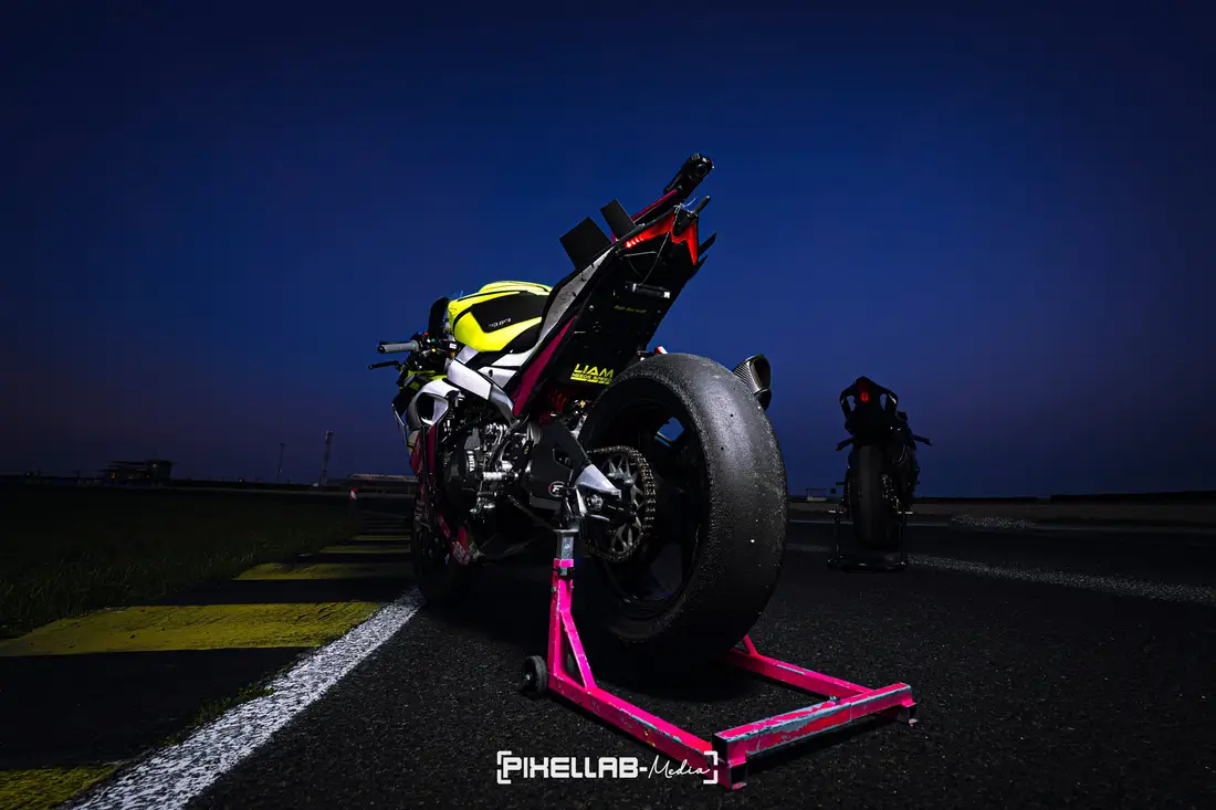 Racing motorcycle on a pink paddock stand at the race track at dusk