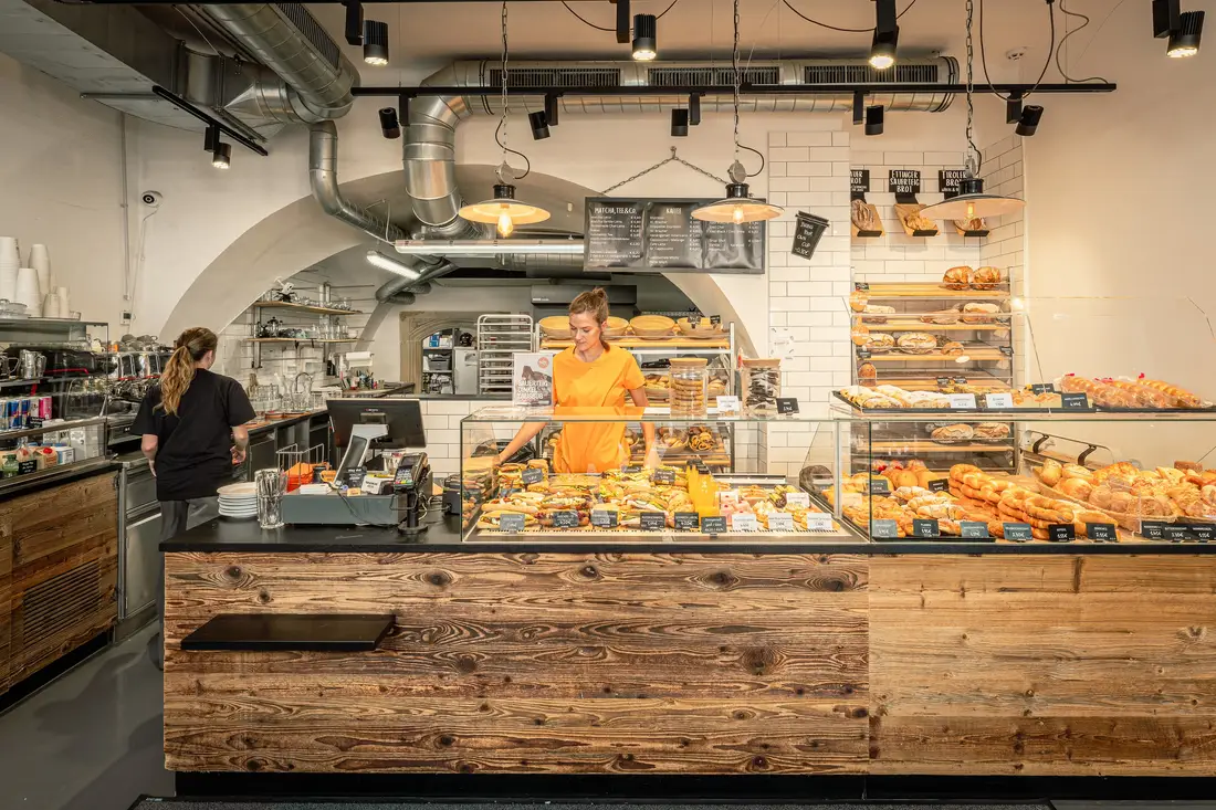 Bäckerei in Krems mit Holztheke und Gebäckvitrine, zwei Mitarbeiterinnen bei der Arbeit