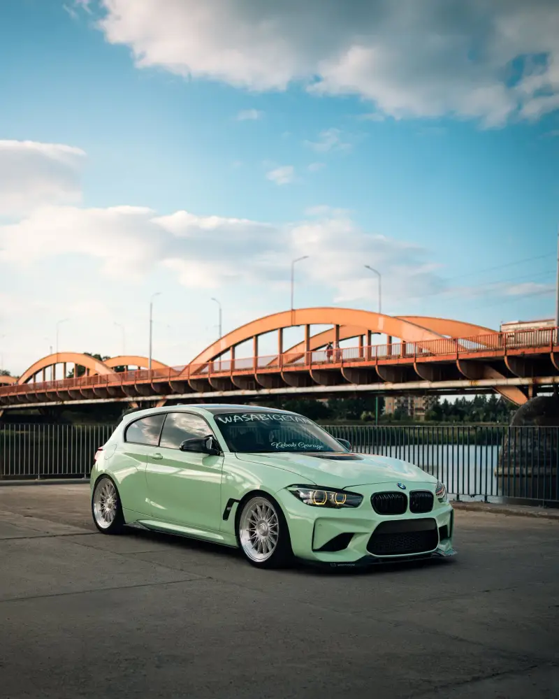 Mintgrüner BMW vor einer roten Bogenbrücke