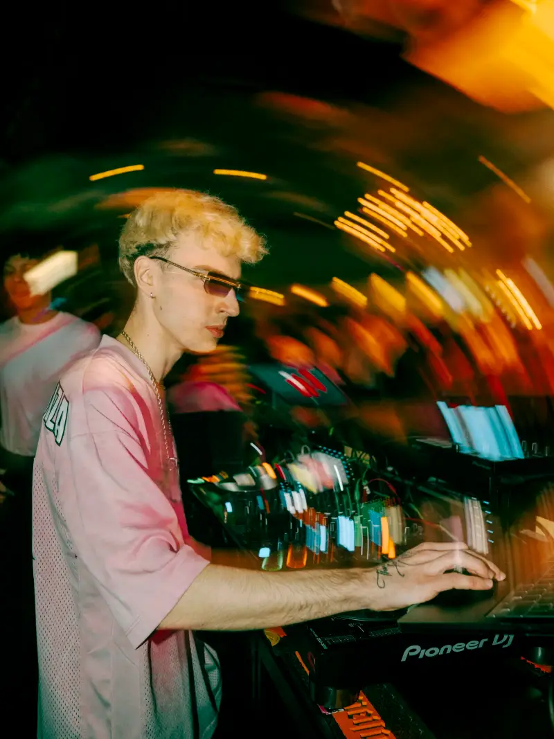 DJ am Mischpult, die Lichter verschwimmen in der Bewegung