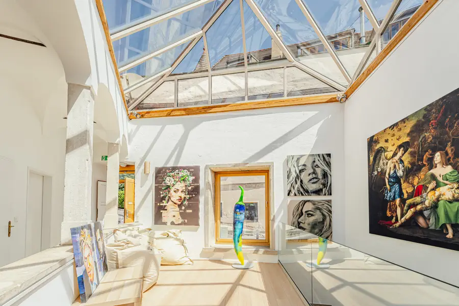 Galerie mit Glasdach und Gemälden an weißen Wänden