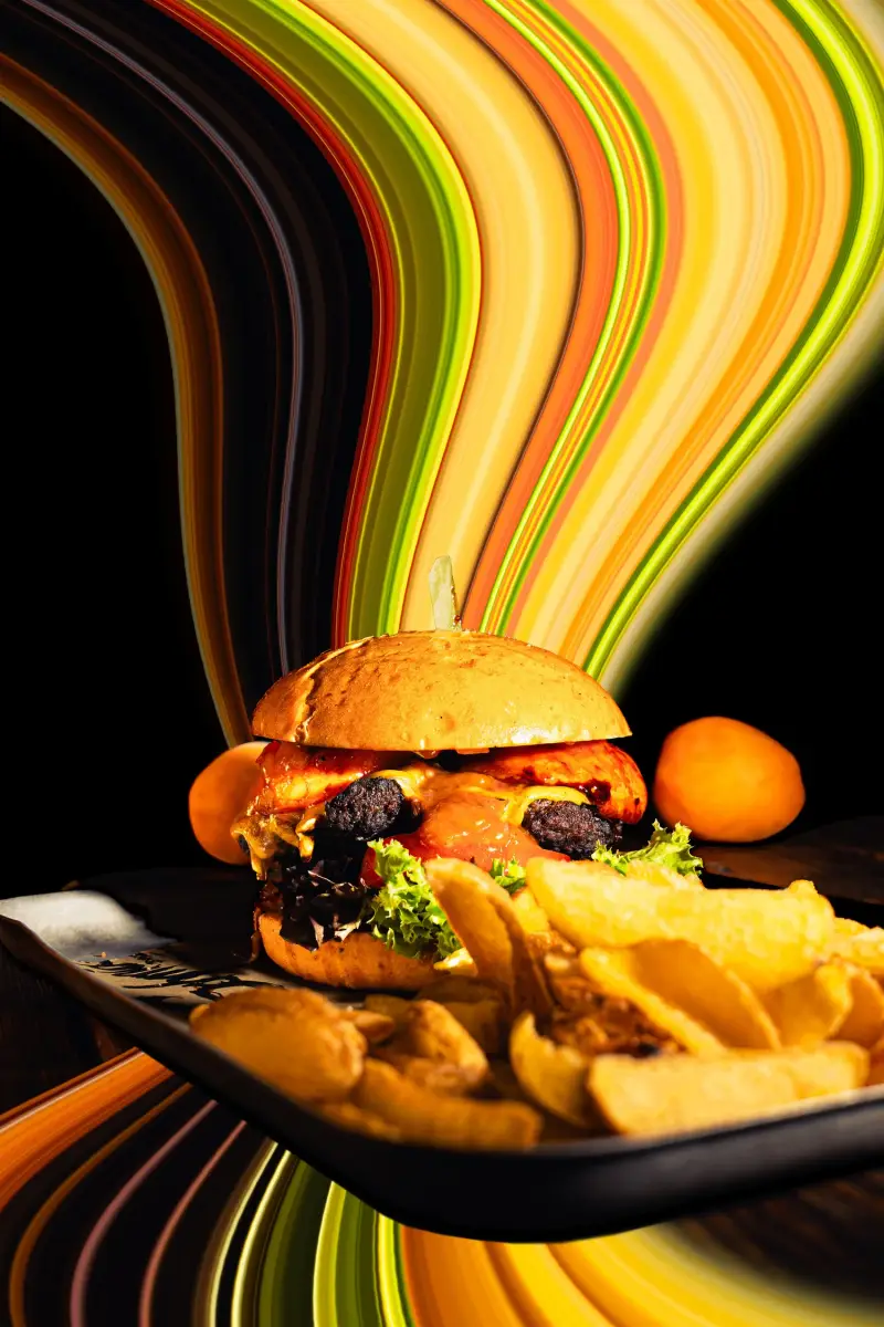 Burger mit Pommes vor bunten Lichtspuren